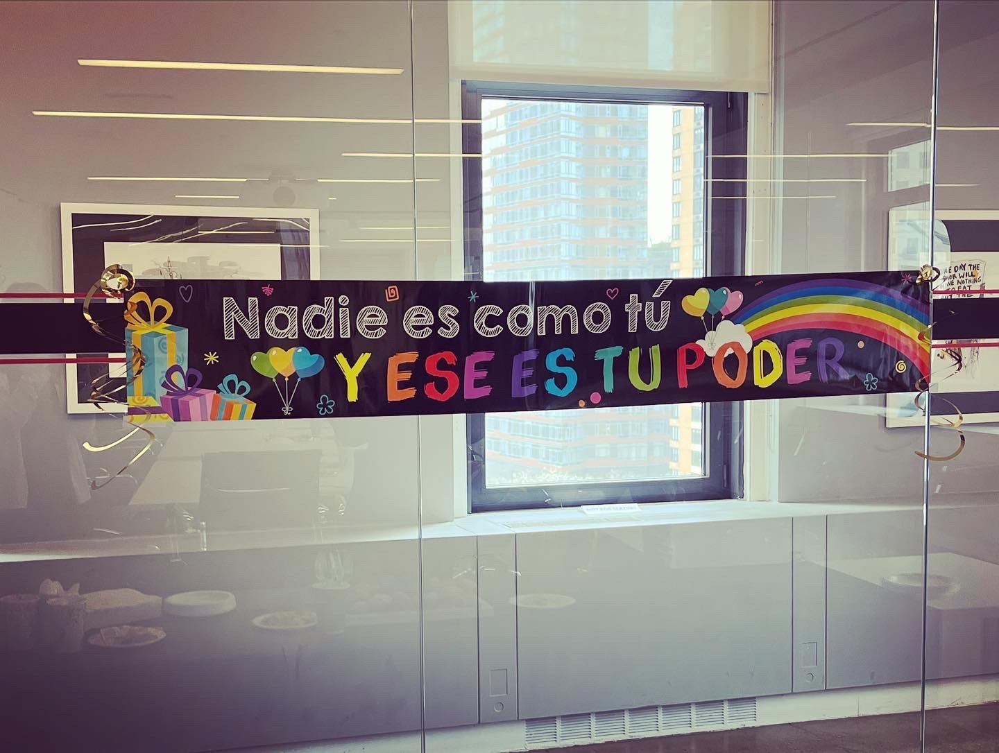 A festive banner on a clear glass window that reads "Nadie es como tu y ese es tu poder" (No one is like you and this is your power)